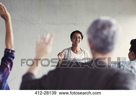 Stock Photo - Teacher calling on students with hands raised in adult education classroom. Fotosearch