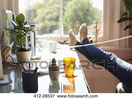 Woman talking on telephone with feet up on desk in sunny home office View Large Photo Image Stock Photo - Woman talking on telephone with feet up on desk in sunny home office. Fotosearch