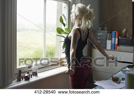 Young woman stretching at window in home office View Large Photo Image Stock Image - Young woman stretching at window in home office. Fotosearch