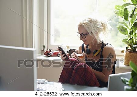 Young woman with headphones and tattoo texting in home office View Large Photo Image Stock Image - Young woman with headphones and tattoo texting in home office. Fotosearch