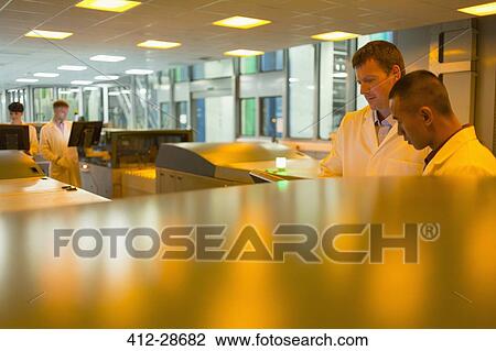 Stock Image - Engineer among printers in printing plant. Fotosearch