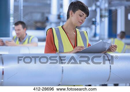 Female worker with clipboard looking down at clipboard in factory View Large Photo Image Stock Photograph - Female worker with clipboard looking down at clipboard in factory. Fotosearch