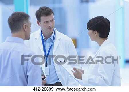 Stock Photo - Scientists and businessman talking in factory. Fotosearch