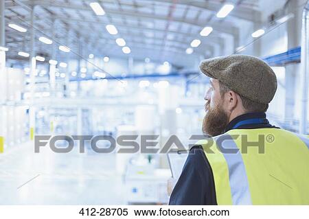 Worker with beard and beret looking out over factory View Large Photo Image Stock Photography - Worker with beard and beret looking out over factory. Fotosearch