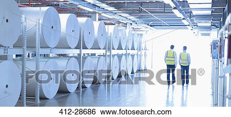 Workers in reflective clothing walking along large paper spools in printing plant View Large Photo Image Stock Photograph - Workers in reflective clothing walking along large paper spools in printing plant. Fotosearch