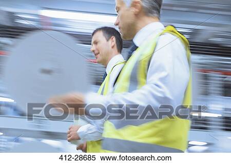 Workers in reflective clothing walking in factory View Large Photo Image Stock Photography - Workers in reflective clothing walking in factory. Fotosearch