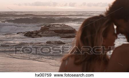 Stock Photo - Affectionate couple cuddling on ocean beach. Fotosearch