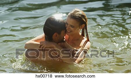Affectionate couple hugging and swimming in sunny lake View Large Photo Image Stock Photo - Affectionate couple hugging and swimming in sunny lake. Fotosearch