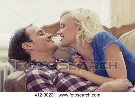 Stock Image - Affectionate couple laying on sofa. Fotosearch