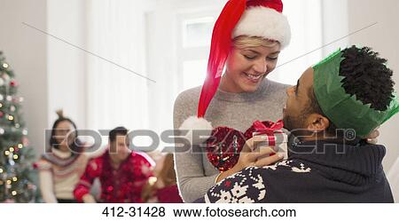 Affectionate couple with Christmas gift in living room View Large Photo Image Stock Photo - Affectionate couple with Christmas gift in living room. Fotosearch
