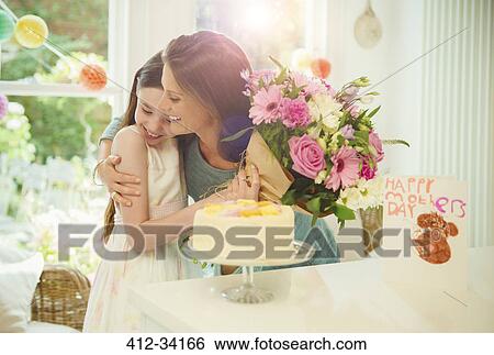 Stock Photograph - Affectionate daughter giving flower bouquet to mother on Mothers Day. Fotosearch