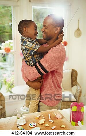 Affectionate father and son hugging next to Easter decorations View Large Photo Image Picture - Affectionate father and son hugging next to Easter decorations. Fotosearch