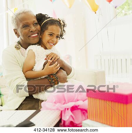 Affectionate grandmother and granddaughter hugging at birthday party View Large Photo Image Stock Photo - Affectionate grandmother and granddaughter hugging at birthday party. Fotosearch