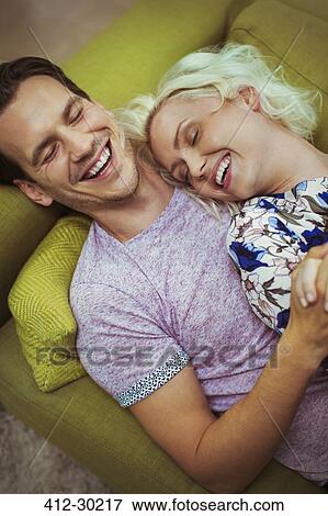 Affectionate laughing couple laying on sofa with eyes closed View Large Photo Image Stock Photo - Affectionate laughing couple laying on sofa with eyes closed. Fotosearch
