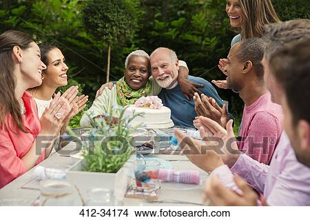 Affectionate multi-ethnic senior couple hugging celebrating anniversary at patio table View Large Photo Image Picture - Affectionate multi-ethnic senior couple hugging celebrating anniversary at patio table. Fotosearch