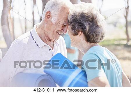 Affectionate senior couple holding yoga mats in park View Large Photo Image Stock Image - Affectionate senior couple holding yoga mats in park. Fotosearch
