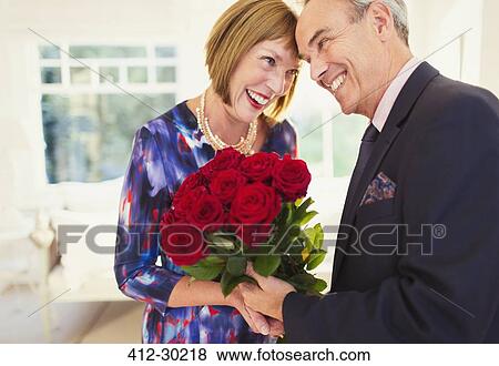 Affectionate well-dressed mature couple with rose bouquet View Large Photo Image Stock Photo - Affectionate well-dressed mature couple with rose bouquet. Fotosearch