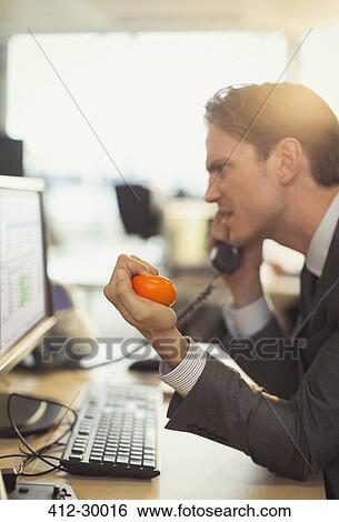 Angry businessman squeezing stress ball and talking on telephone at computer in office View Large Photo Image Stock Photograph - Angry businessman squeezing stress ball and talking on telephone at computer in office. Fotosearch