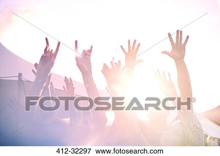 Stock Photo - Arms raised cheering at sunny music festival. Fotosearch