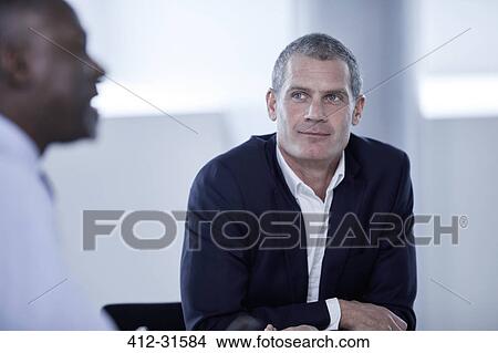 Picture - Attentive businessman listening to colleague in meeting. Fotosearch