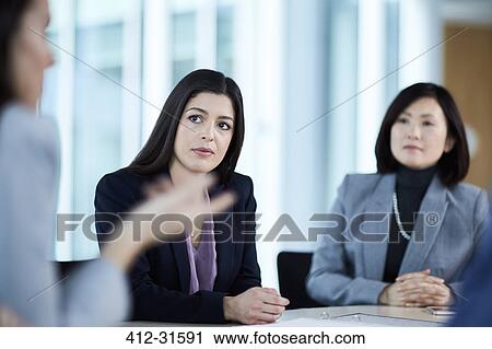 Stock Image - Attentive businesswoman listening to colleague in meeting. Fotosearch