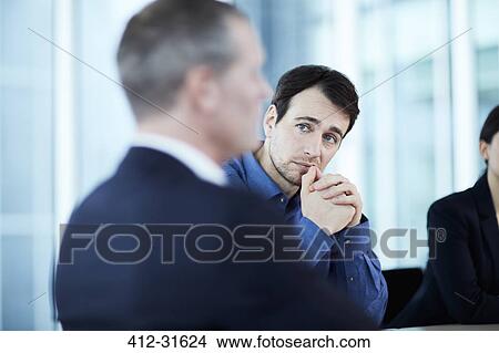 Picture - Attentive serious businessman listening to colleague in meeting. Fotosearch