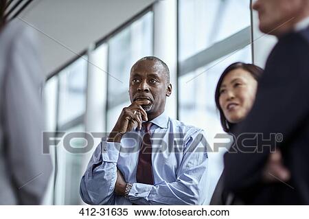 Stock Photography - Attentive serious businessman listening to colleagues. Fotosearch
