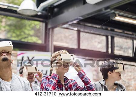 Stock Image - Audience trying virtual reality simulator glasses at technology conference. Fotosearch