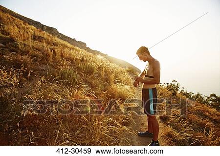 Bare chested male runner on trail checking smart watch View Large Photo Image Stock Photo - Bare chested male runner on trail checking smart watch. Fotosearch