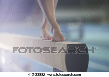 Stock Image - Bare feet of female gymnast performing on balance beam. Fotosearch