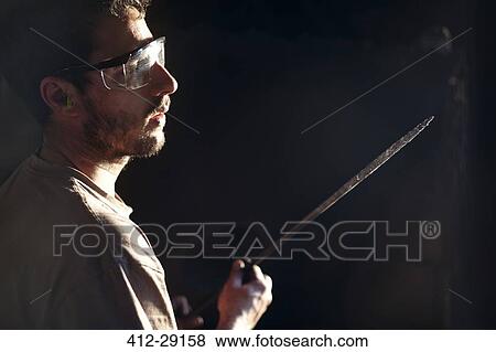 Blacksmith examining iron blade View Large Photo Image Stock Photo - Blacksmith examining iron blade. Fotosearch