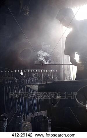 Blacksmith holding steaming wrought iron over anvil in forge View Large Photo Image Stock Image - Blacksmith holding steaming wrought iron over anvil in forge. Fotosearch