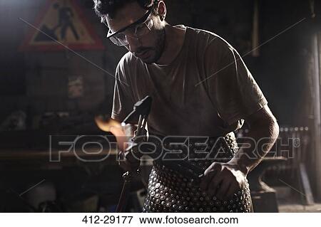 Stock Photo - Blacksmith using blowtorch in forge. Fotosearch