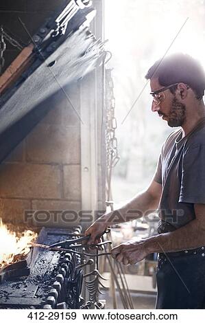 Stock Photo - Blacksmith working over fire in forge. Fotosearch