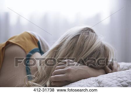 Stock Photo - Blonde woman laying on bed. Fotosearch