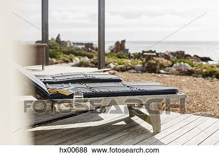 Book and water at lounge chair on patio overlooking ocean View Large Photo Image Stock Photo - Book and water at lounge chair on patio overlooking ocean. Fotosearch