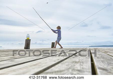 Boy fishing off lakeside dock View Large Photo Image Stock Photo - Boy fishing off lakeside dock. Fotosearch