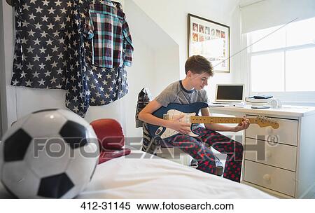 Boy playing electric guitar in bedroom View Large Photo Image Stock Photography - Boy playing electric guitar in bedroom. Fotosearch