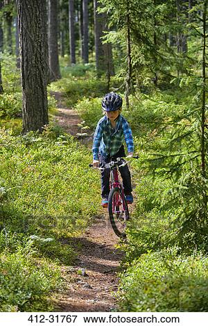 Stock Photo - Boy riding bicycle on trail in woods. Fotosearch