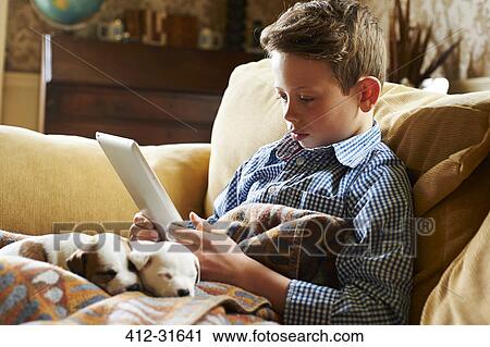 Boy using digital tablet with puppies in lap View Large Photo Image Stock Image - Boy using digital tablet with puppies in lap. Fotosearch
