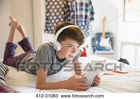 Boy with headphones listening to music on digital tablet View Large Photo Image Stock Image - Boy with headphones listening to music on digital tablet. Fotosearch