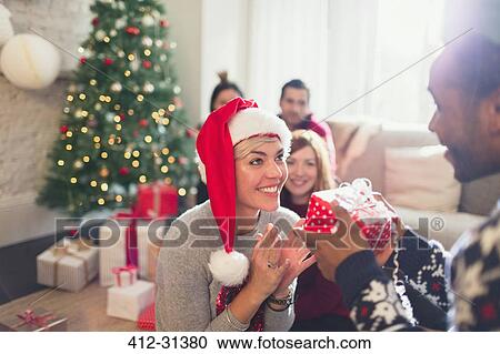 Stock Image - Boyfriend giving excited girlfriend Christmas gift. Fotosearch