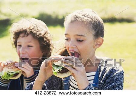 Brother and sister eating hamburgers outside View Large Photo Image Stock Image - Brother and sister eating hamburgers outside. Fotosearch