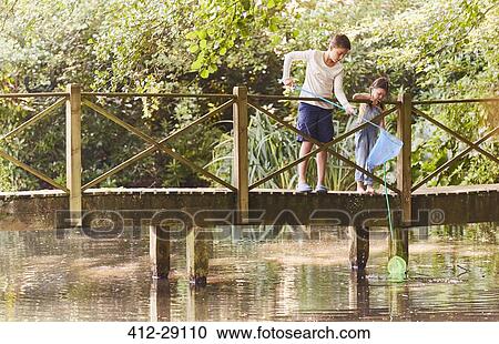 Brother and sister fishing with nets at footbridge over pond View Large Photo Image Stock Image - Brother and sister fishing with nets at footbridge over pond. Fotosearch