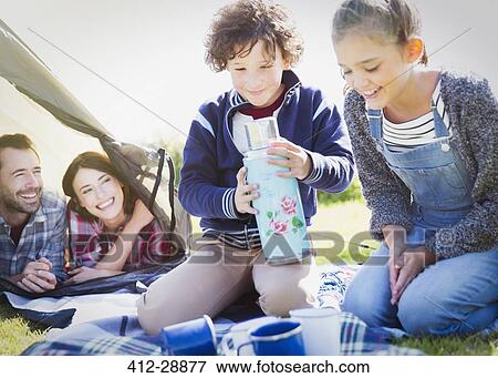 Stock Photo - Brother and sister holding insulated drink container outside tent. Fotosearch