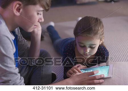 Stock Image - Brother and sister playing game on digital tablet. Fotosearch
