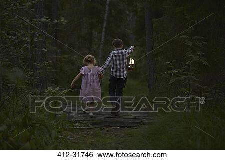 Brother and sister walking with lantern over footbridge in woods View Large Photo Image Stock Photograph - Brother and sister walking with lantern over footbridge in woods. Fotosearch