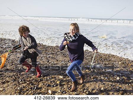 Stock Photo - Brother and sister with nets running from ocean onto beach. Fotosearch