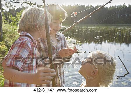 Stock Photo - Brothers and sister fishing at sunny pond. Fotosearch