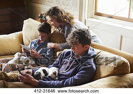 Brothers and sister using digital tablet and cell phone with puppies in laps View Large Photo Image Stock Photograph - Brothers and sister using digital tablet and cell phone with puppies in laps. Fotosearch